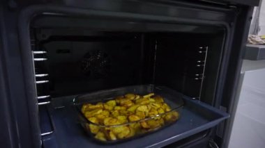 Patatesler fırında cam bir kapta pişiyor.