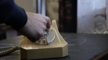 Eski bir sabit telefon hattından bir adamın telefon numarasını çevirdiği görüntüler.