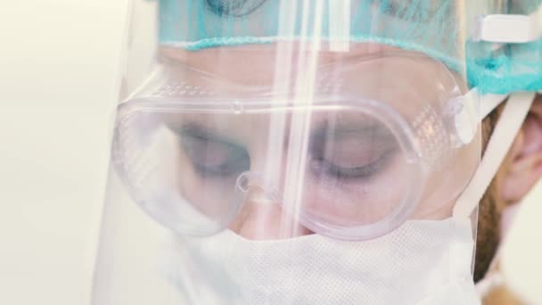 勤務中の男性外科医の目を保護マスクや医療用眼鏡で塞ぐ 疫学的保護は — ストック動画