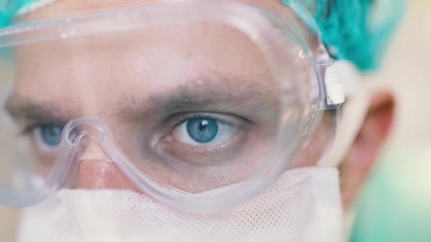 勤務中の男性外科医の目を保護マスクや医療用眼鏡で塞ぐ 疫学的保護は — ストック動画