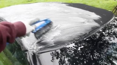 footage of cleaning the tarpaulin roof of the convertible with foam cleaner.