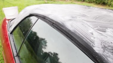 footage of cleaning the tarpaulin roof of the convertible with foam cleaner.