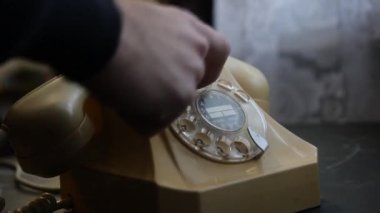 Eski bir sabit telefon hattından bir adamın telefon numarasını çevirdiği görüntüler.