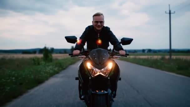 Junger Mann Lederjacke Und Brille Fährt Abends Motorrad Auf Der — Stockvideo