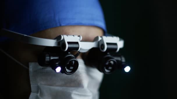 Footage Surgeon Wearing Binocular Magnifying Glasses Operating Patient Dark Operating — Stock Video