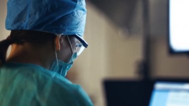 Cerrah, hasta hakkındaki bilgileri bir sağlık ofisinin ameliyathanesinde monitörden inceler.