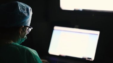 Cerrah, hasta hakkındaki bilgileri bir sağlık ofisinin ameliyathanesinde monitörden inceler.