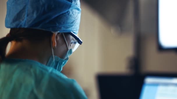 外科医は診療所の手術室のモニターで患者の情報を調べ — ストック動画