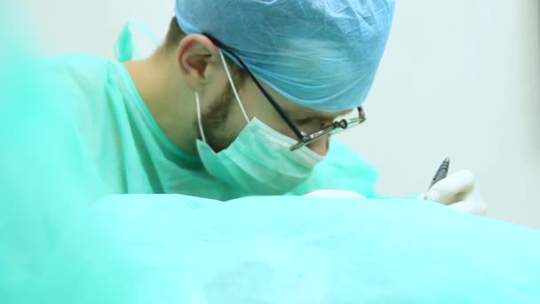 手術室で患者を手術する眼鏡の男性外科医 — ストック動画