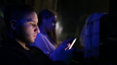 Gece otobüste seyahat ederken akıllı telefon kullanan bir çiftin görüntüleri.