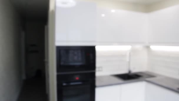 Bílý kompaktní kuchyňský interiér s vestavěnými domácími spotřebiči