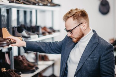 Ayakkabı mağazasındaki adam ayakkabı alır.