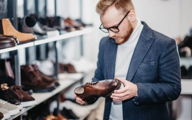 Ayakkabı mağazasındaki adam ayakkabı alır.