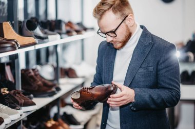 Ayakkabı mağazasındaki adam ayakkabı alır.