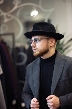 Elbise mağazasında şapka deneyen bir adam.