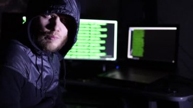 Siyah başlıklı bilgisayar korsanı birkaç ekranlı bilgisayarlar üzerinde çalışıyor.