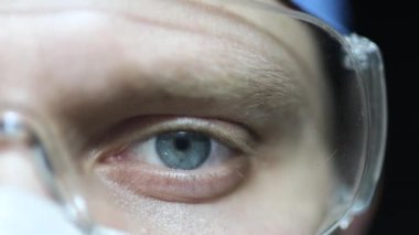 Gözlüklü erkek doktor ve maske yakın plan, gözler dikkatlice bakar..