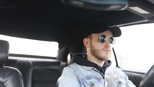 Junger Bärtiger Autofahrer Fährt Tagsüber Mit Mütze Und Sonnenbrille — Stockvideo