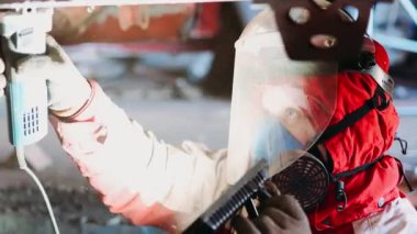 Adam koruyucu epikerovka fabrikasında çalışıyor, yüz kalkanı ve solunum cihazı, çalışma yüzeyini projektörle aydınlatıyor..