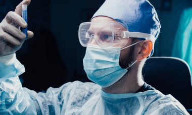 Erkek bilim adamı laboratuvar asistanı test tüpündeki bir ilacı inceliyor..