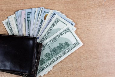 Tahta bir arka planda kahverengi bir cüzdanda dolar banknotları.
