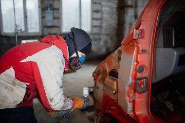 Solunum cihazındaki adam bir arabayı kırmızıya boyuyor, bir kamyoneti tamir ediyor..