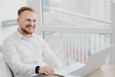 Ofiste dizüstü bilgisayarla çalışan Kafkasyalı sarışın adam.