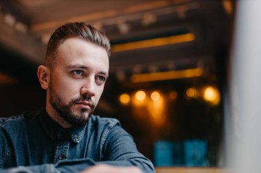 Serbest çalışan bir erkek, rahat bir kafede oturur ve internette bir dizüstü bilgisayarla çalışır.