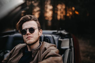 Üstü açık, iddialı sürücüsü olan güneş gözlüklü şık bir adam..