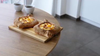 İki khachapuri ve iki fincan kahve. Ofisteki ahşap masada bir tabak Gürcü mutfağı.