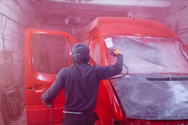 Solunum cihazındaki adam bir arabayı kırmızıya boyuyor, bir kamyoneti tamir ediyor..