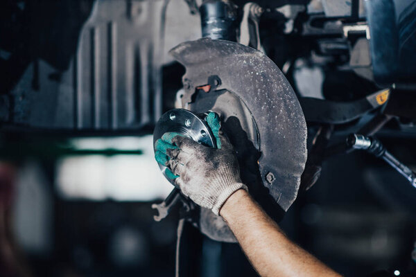 мужчина меняет ступицу колеса с подшипником колеса в автомобиле