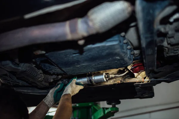 Replacing the fuel filter of a diesel car in a car service, dismantling the fuel filter under the bottom of the car.