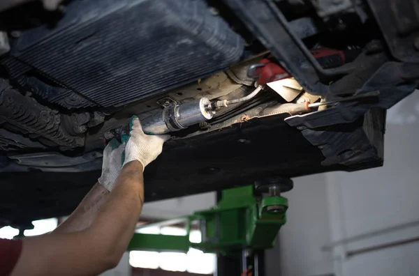 Replacing the fuel filter of a diesel car in a car service, dismantling the fuel filter under the bottom of the car.