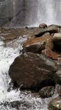 Witness the power and mesmerizing beauty of the waterfall as it gracefully cascades over rugged rocks. This serene scene captures the essence of nature's natural energy and calming rhythm.