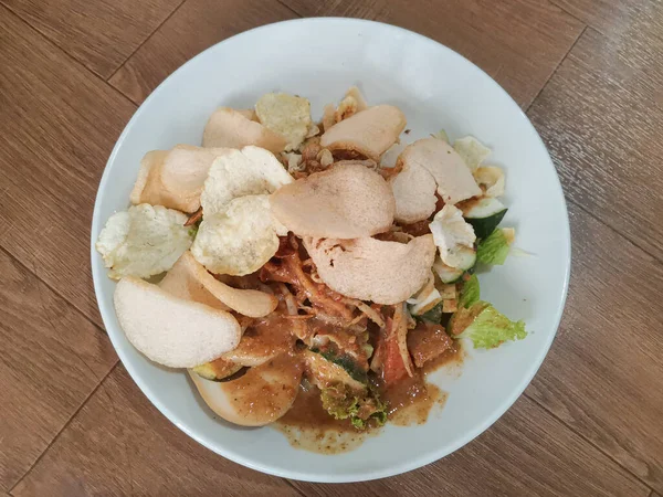 Lezzetli Endonezya Gado-Gado 'sunun yakın plan çekimi. Ahşap bir masanın üzerinde fıstık sosu ve karides krakerleri..