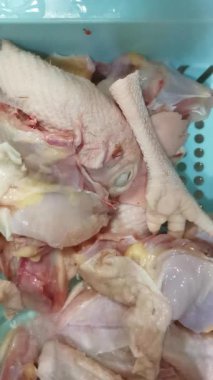 Bu video pişirmek için çiğ tavuk parçaları yıkama ve hazırlama sürecini gösteriyor. Mutfaktaki kümes hayvanlarının hijyen ve güvenli bir şekilde kullanılması ve gıda güvenliğinin sağlanması üzerinde duruluyor..