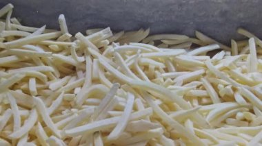 Bu videoda kızartılmaya ve servis edilmeye hazır bir dizi pişmemiş patates kızartması var. Bu popüler atıştırmalığın ham formunu sergiliyor, dokusunu ve bolluğunu vurguluyor.