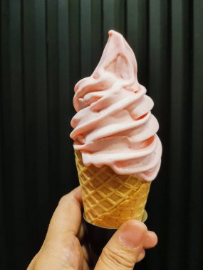 Waffle külahında tutulan kremalı, yumuşak çilekli dondurmaya yakın dur. Yumuşak kıvrımlar ve parlak renkler arka planda en düşük seviyede yer alacaktır..