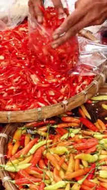 Yeni dilimlenmiş kırmızı biberleri plastik poşetlere doldurup kalabalık bir markette renkli kırmızı biber çeşitlerinin olduğu sepetlerin üzerine koyun..