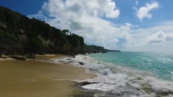 Weiße Wellen brechen an der wilden Felsküste von Bali, Asien. Drohnenvideo mit Luftaufnahme des paradiesischen Strandes mit hohen Klippen und weißen Wolken aus Indonesien — Stockvideo
