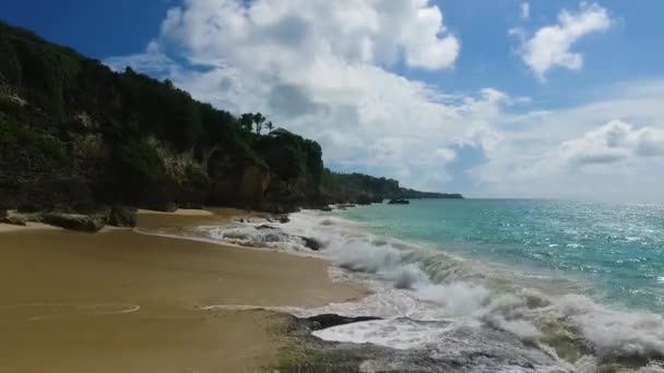 White waves breaking on the wild Bali rocky coast, Asia. Drone (copter) video with aerial view of the paradise beach with high cliffs and white clouds made in Indonesia — Stock Video