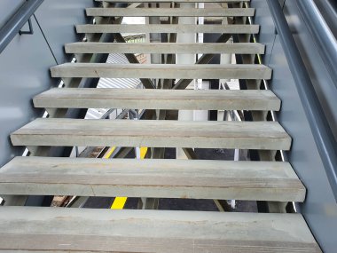 Çağdaş bir merdiven uçuşu, hafif ahşap basamaklar ve açık basamaklar, modern mimari iç mimarinin parlak metal tırabzanları tarafından çevrelenmiş..