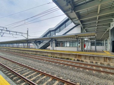 Tangerang, Banten, Endonezya, 1 Aralık 2025. Jatake İstasyonu inşaatta. Bulutlu bir günde ıssız bir tren istasyonu manzarası, paralel rayları, uzun bir platformu ve arka planda çağdaş bir istasyon binasını gösteriyor..