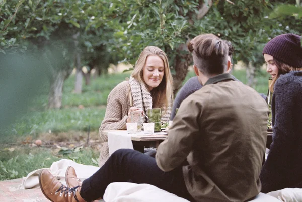 People sitting on the ground in Apple orchard — Stock Photo, Image