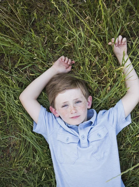 Pojken ligga på gräs. — Stockfoto