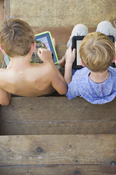 Brothers playing on digital tablets — Stock Photo, Image