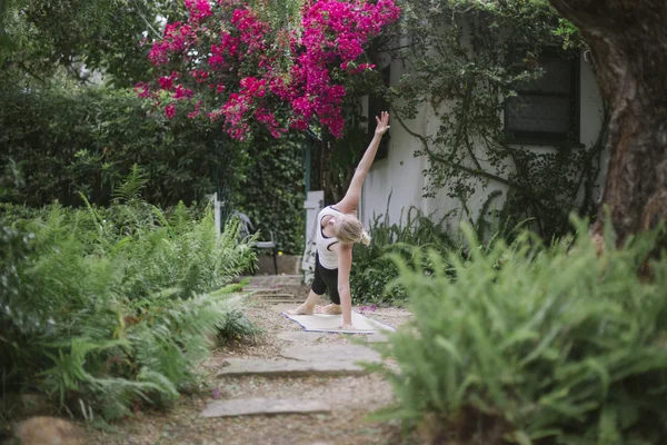 Mujer haciendo yoga en un jardín . — Foto de Stock