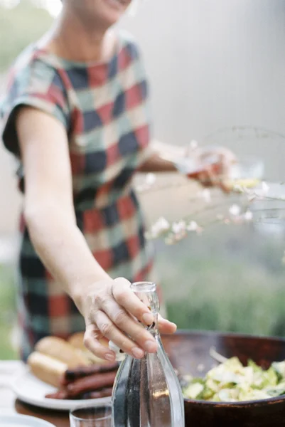 Mujer sosteniendo dos vasos y botella - foto de stock