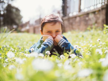 Papatyalarla çevrili, doğa güzelliğine dalmış çimenlerin üzerinde yatan ve gülümseyen küçük bir çocuk. Sahne kaygısız bir neşe anı yakalıyor ve dışarıyla bağlantı kuruyor..